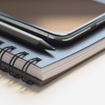 Cuaderno, celular y lápiz