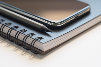 Cuaderno, celular y lápiz